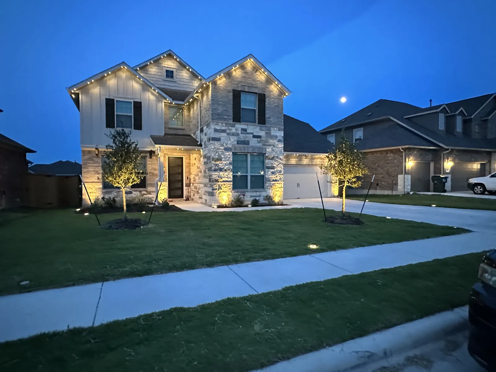 Home facade and walkway lit with warm landscape lighting at dusk