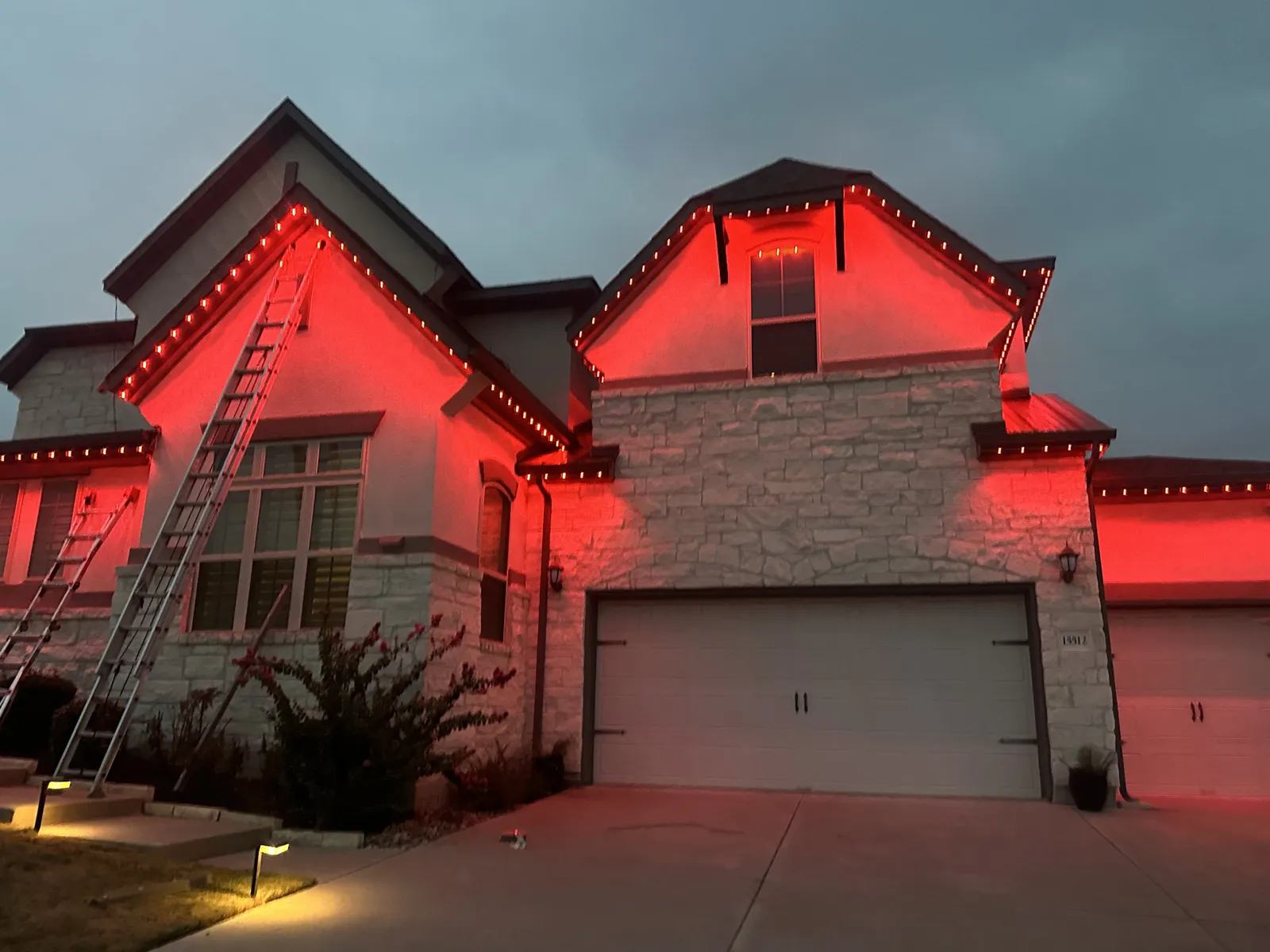 Home lit in red permanent roofline lighting at night