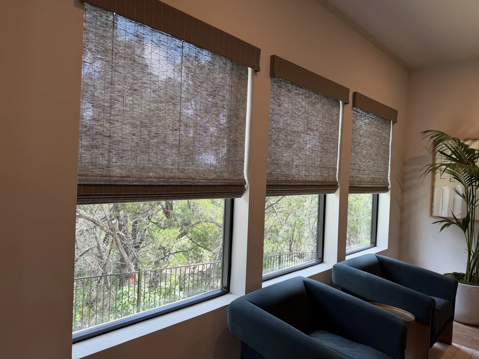 Solar shades filtering daylight over a seating area with a view of trees