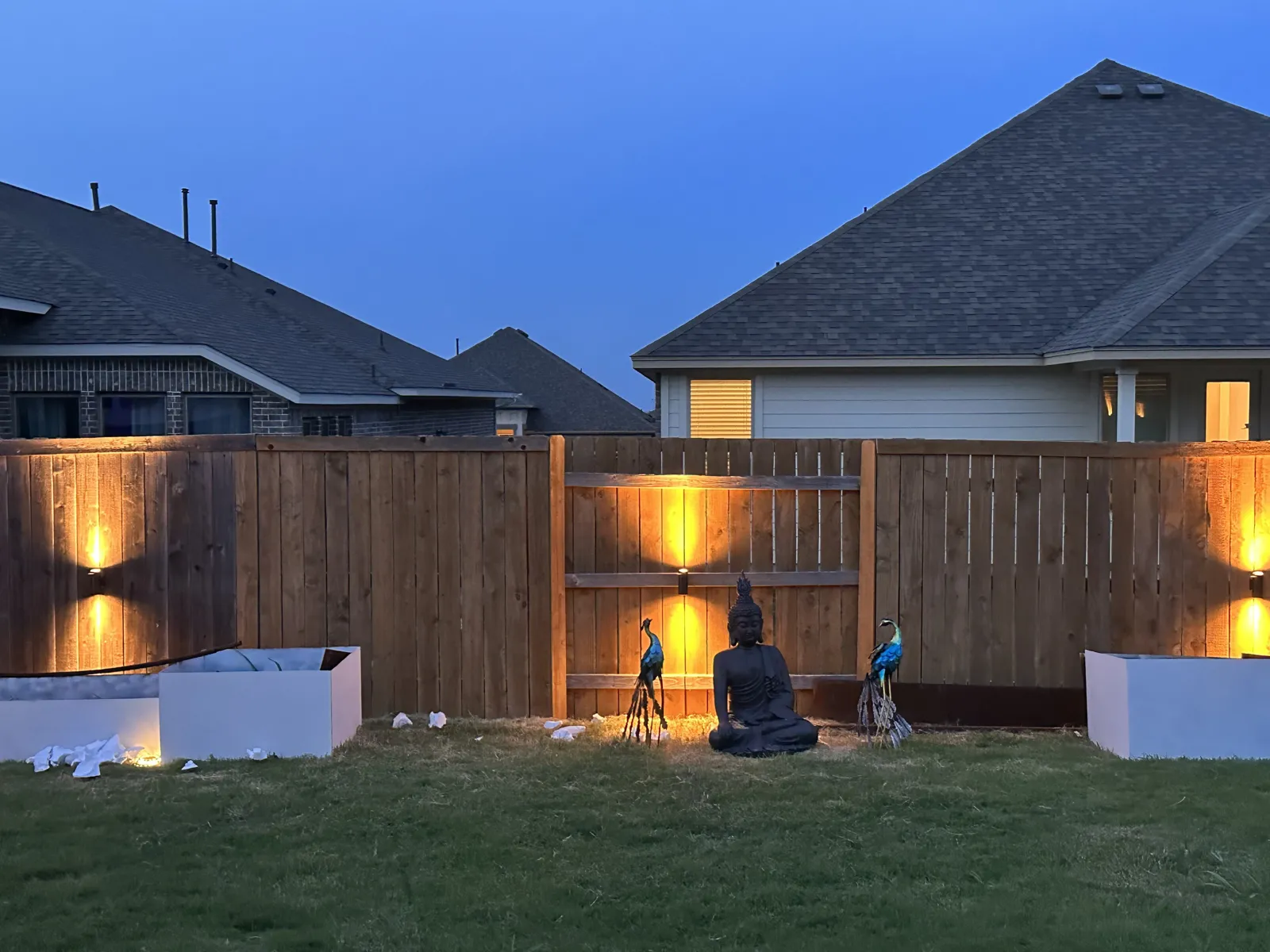 Backyard fence and wall lit with warm accent lighting