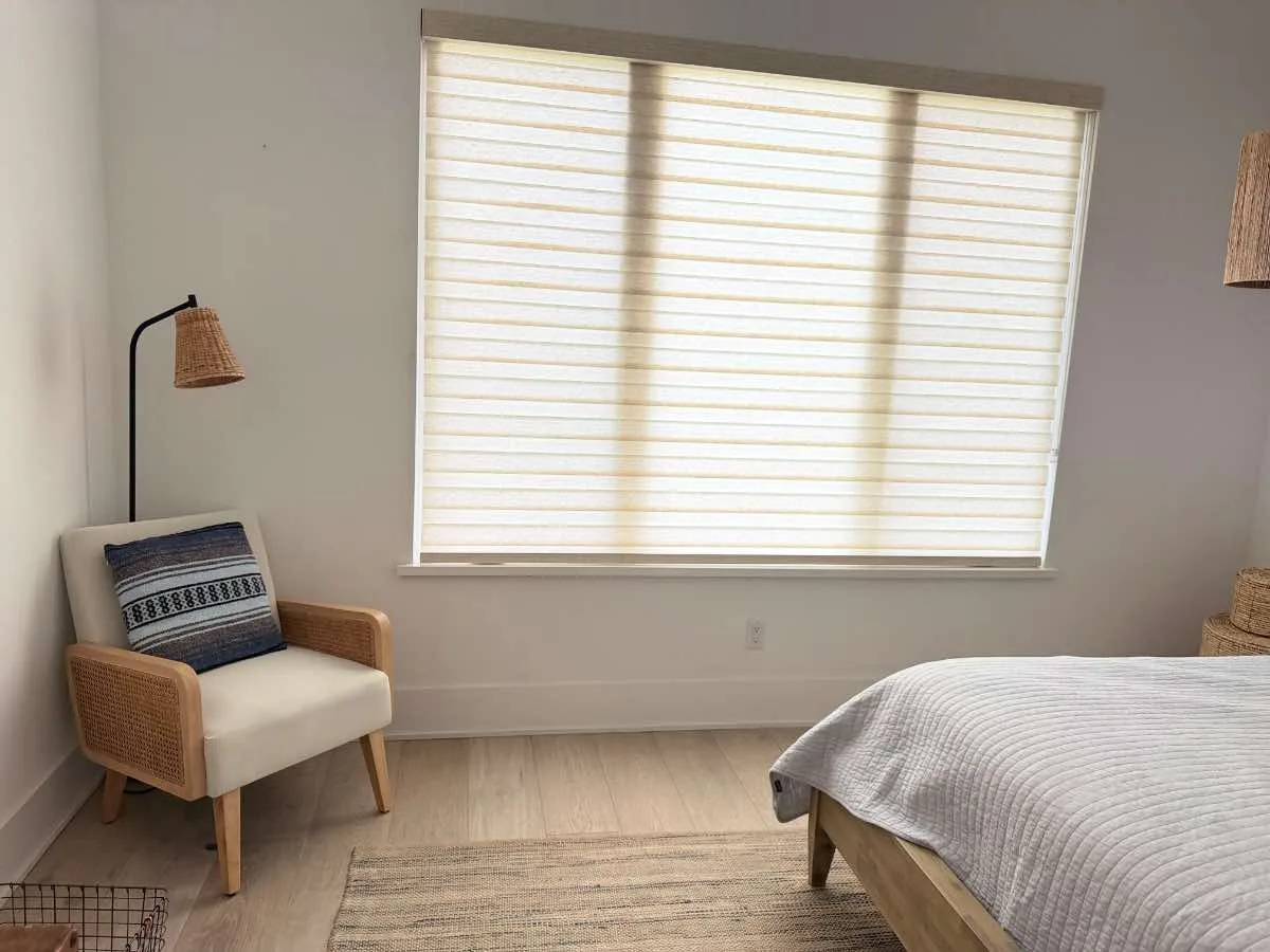 Bedroom with a wide window covered by custom zebra blinds