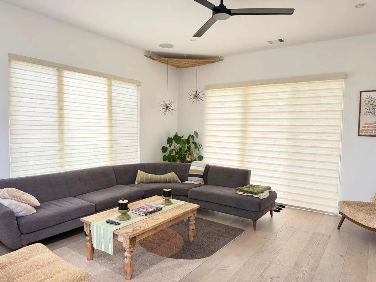 Living room with motorized light-filtering shades across three tall windows