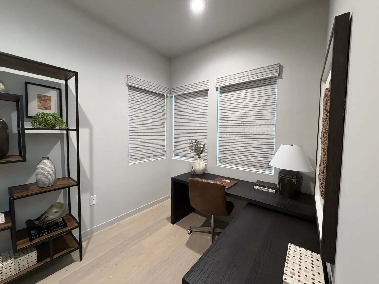 Home office with wood-tone blinds on a corner window