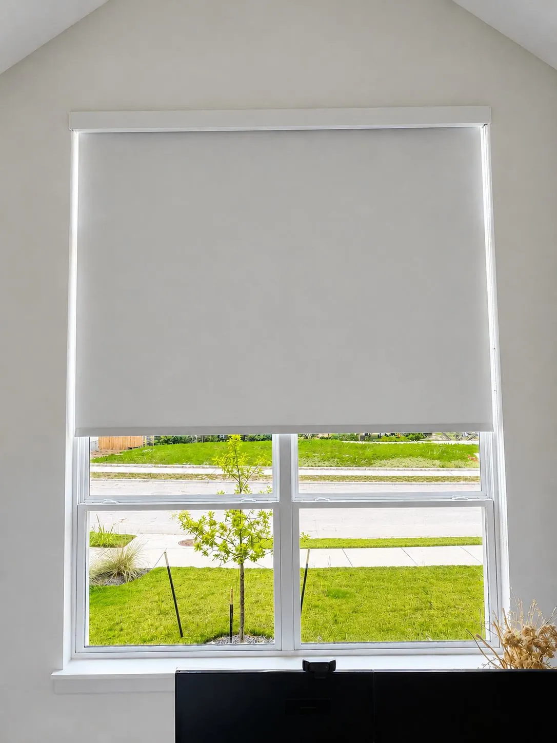 Motorized roller shade lowered over a bright window